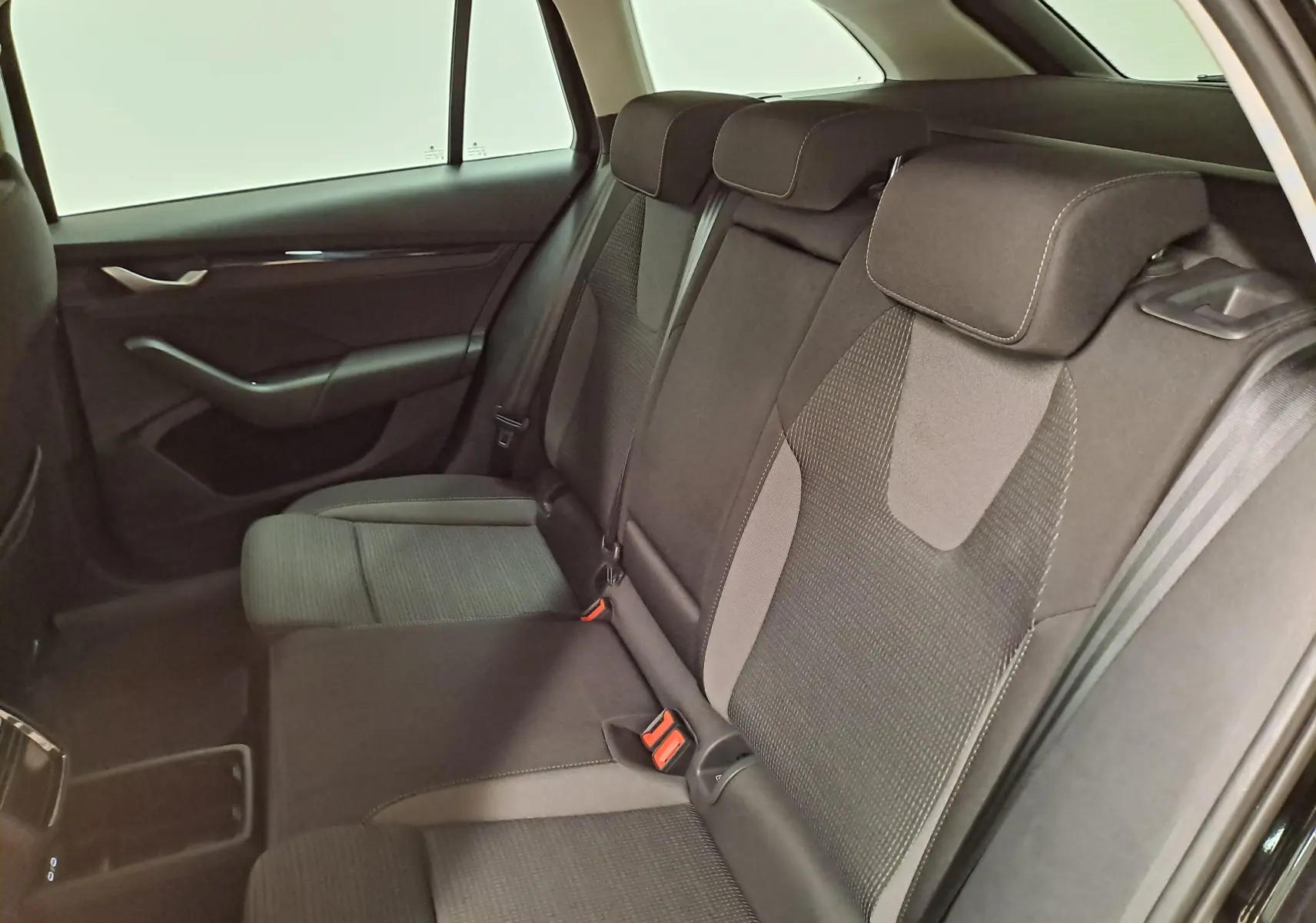 Vue intérieure arrière côté gauche des sièges arrière en tissu gris du Skoda Octavia Combi 1.5 TSI 2025 Noir Magic.