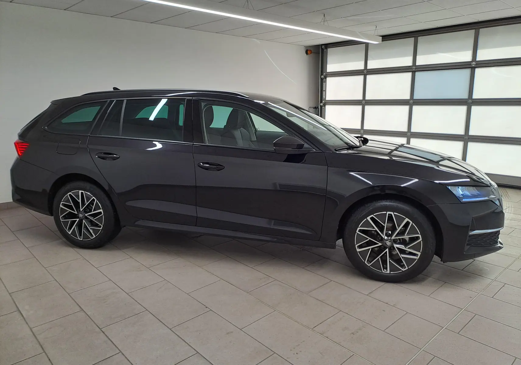 Vue de profil côté gauche d'une Skoda Octavia Combi 2025 noire Magic nacré avec jantes alliage 17'' Slagard Aero noir polies.