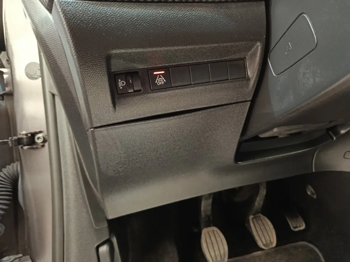 Vue intérieure côté gauche du tableau de bord d'une Peugeot 208 2020 avec commandes d'assistance et pédales visibles.