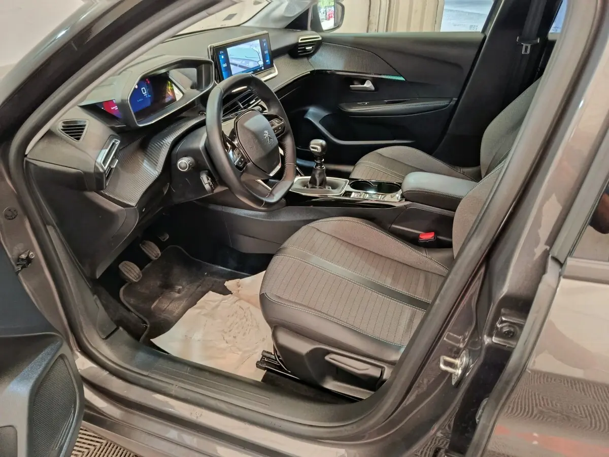 Intérieur avant droit de Peugeot 208 2020 gris, volant cuir multifonctions, écran tactile et tableau de bord numérique.