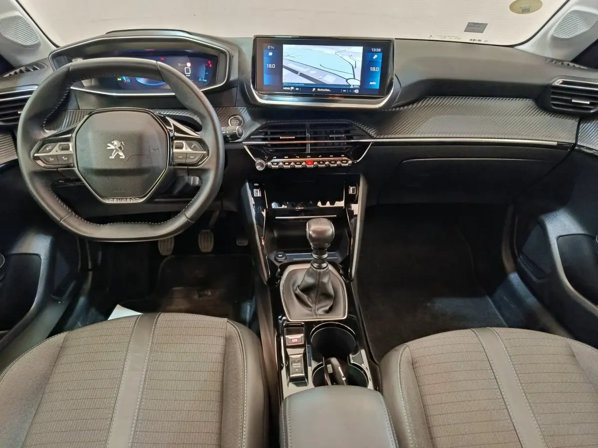 Vue intérieure avant de la Peugeot 208 BlueHDi 100 avec tableau de bord noir et écran tactile central 10 pouces.