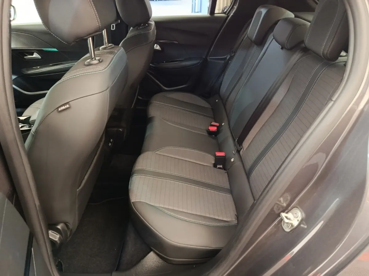Vue côté droit des sièges arrière noirs en tissu et cuir dans une Peugeot 208 2020, porte ouverte.