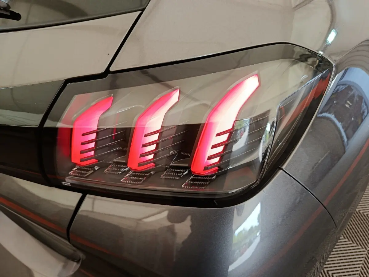 Gros plan sur le feu arrière droit rouge et noir d’une Peugeot 208 gris métallisé, version 2020.