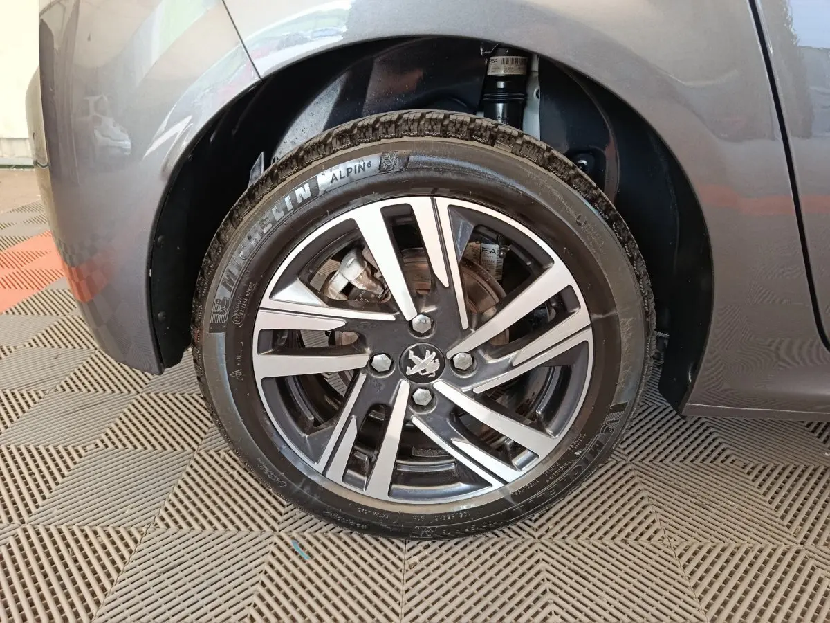 Gros plan sur la roue avant droite grise d'une Peugeot 208 avec jante alliage et pneu Michelin Alpin 6.