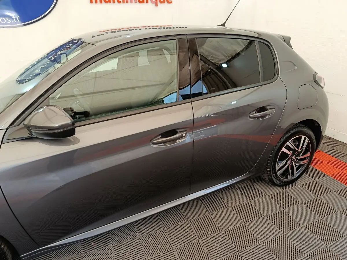 Profil droit d'une Peugeot 208 gris métallisé, mettant en valeur les jantes alliage et les rétroviseurs électriques.