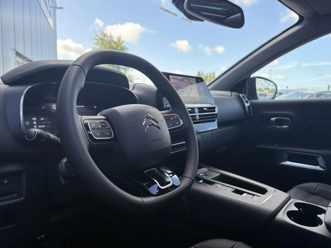 Vue intérieure côté conducteur du Citroën C5 Aircross 2025, tableau de bord et volant noirs avec écran tactile central.
