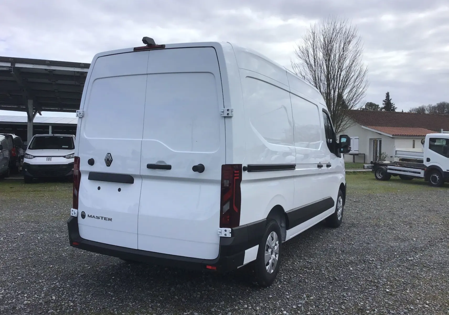 Vue 3/4 arrière droite d’un Renault Master blanc 2026, fourgon utilitaire avec portes arrière fermées sur parking extérieur.