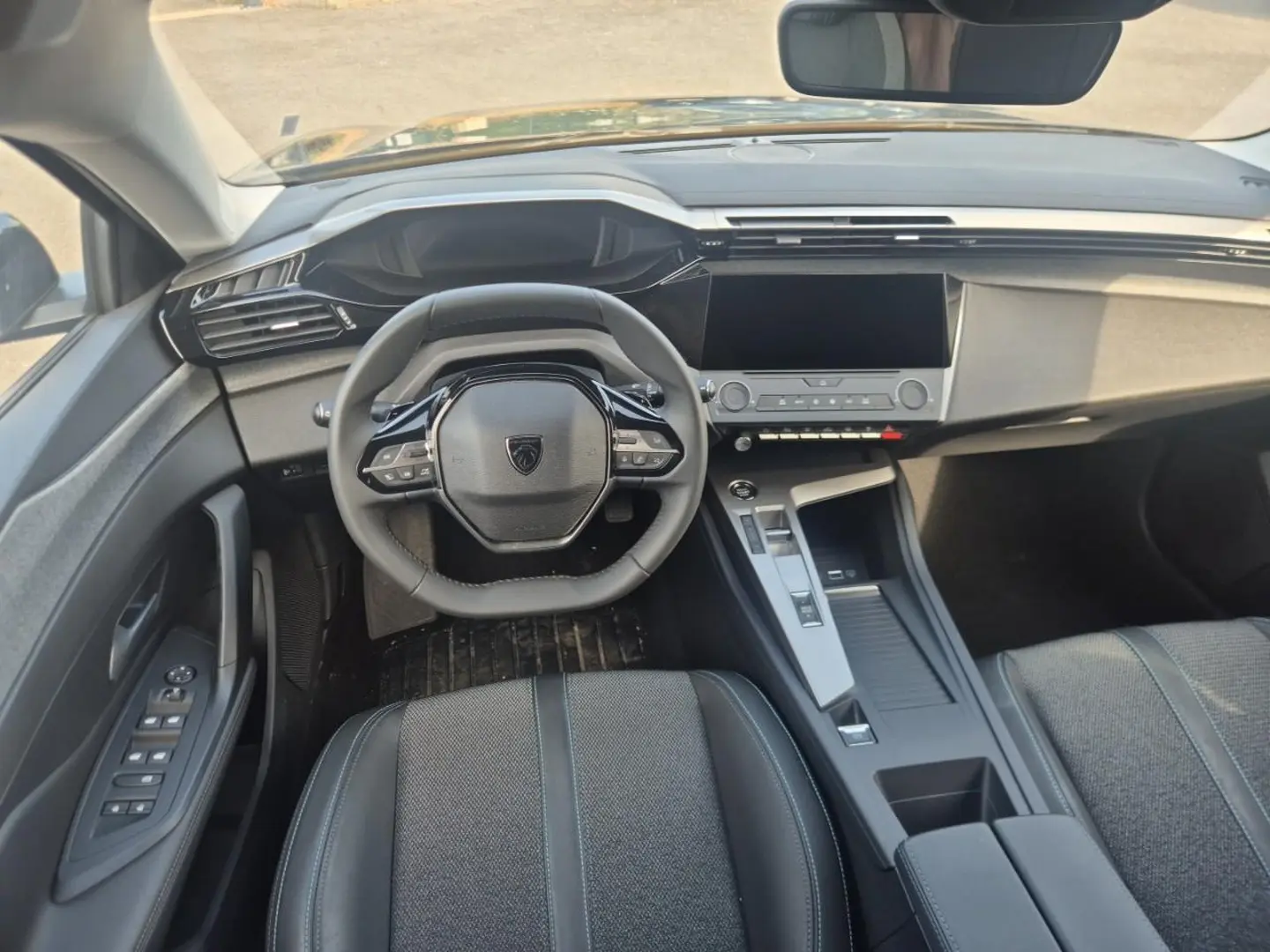 Vue intérieure avant de la Peugeot 308 noire 2025, avec volant multifonction et écran tactile central.