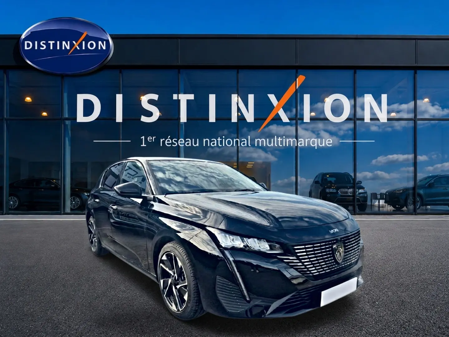 Peugeot 308 noire vue en 3/4 avant droit devant une vitrine Distinxion, avec jantes alu et phares LED allumés.