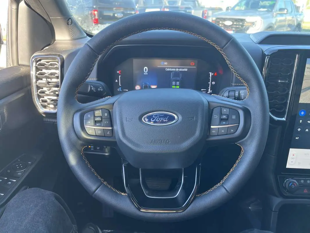 Vue centrée sur le volant cuir noir du Ford Ranger 2026 avec coutures marron et tableau de bord numérique.