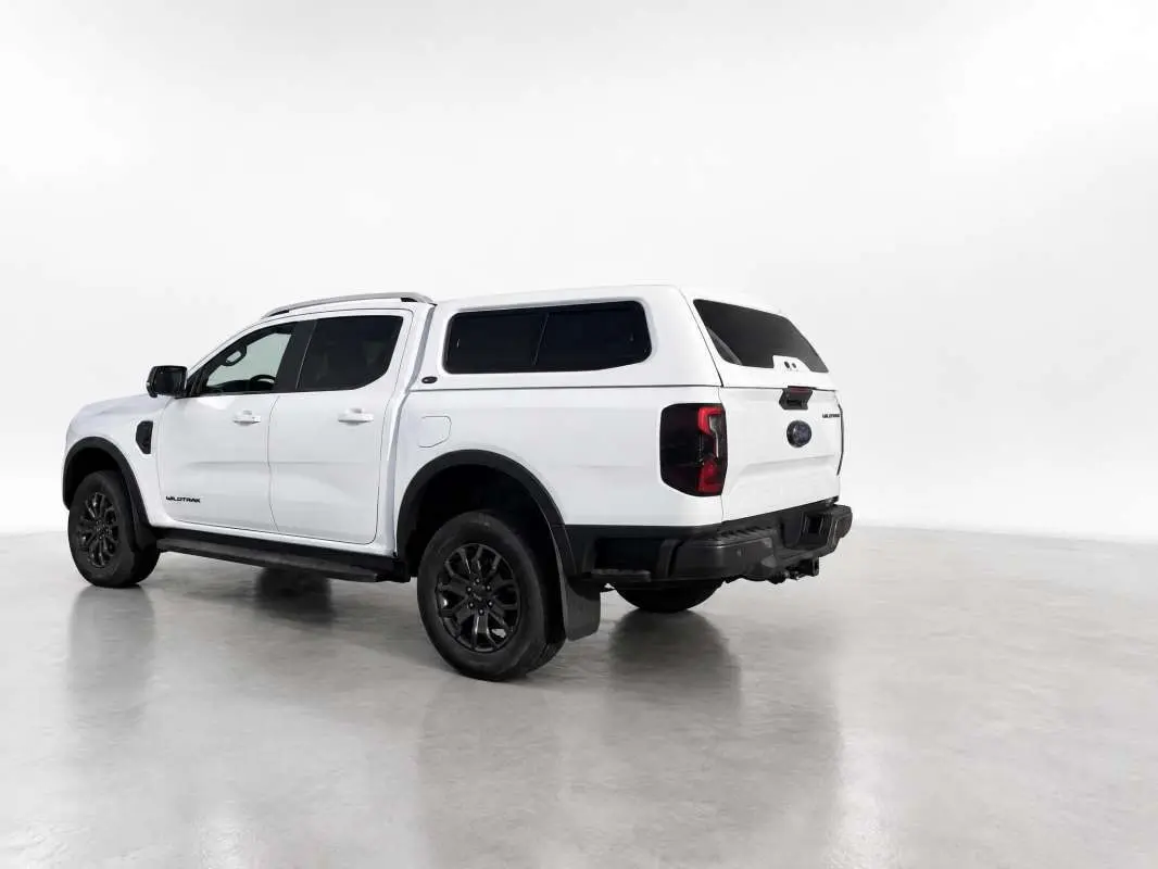 Ford Ranger Wildtrak blanc glacier vu en 3/4 arrière droit avec hardtop vitré et jantes noires.