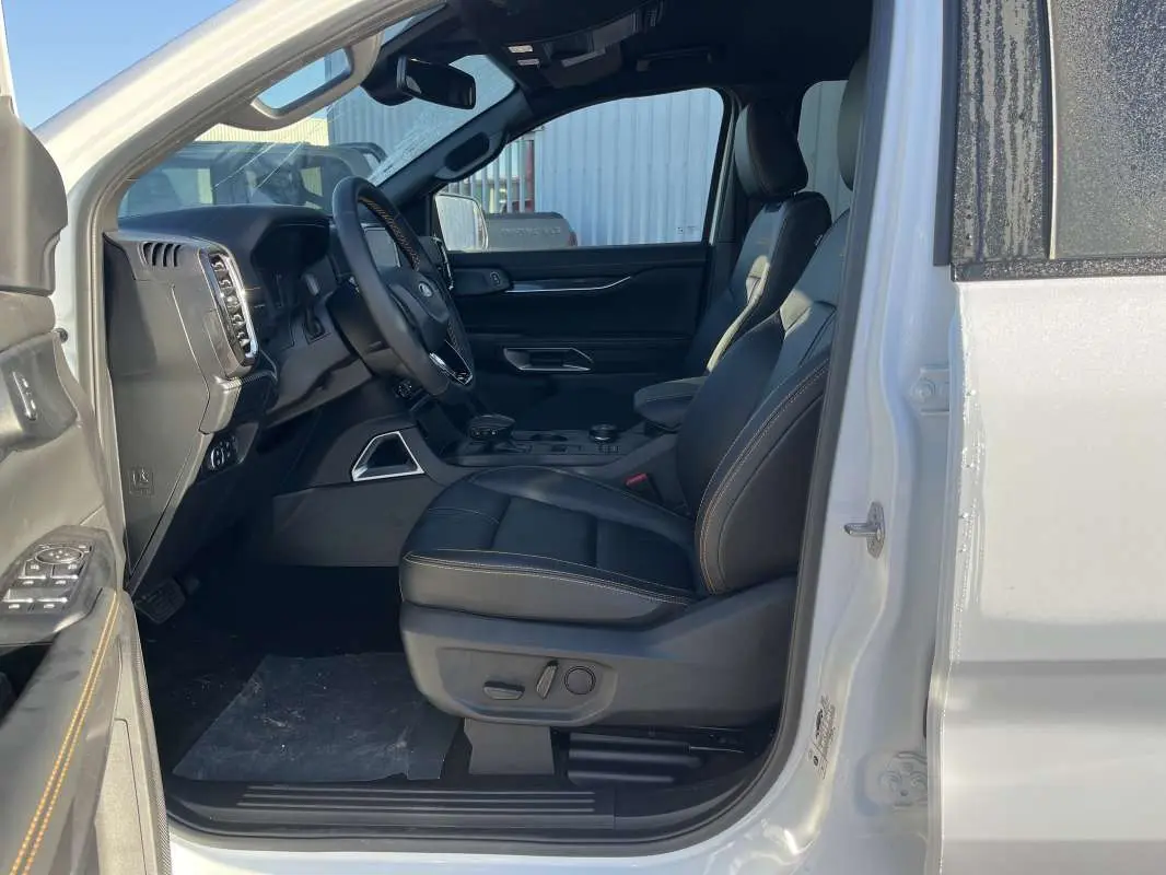 Vue intérieure côté conducteur du Ford Ranger blanc glacier 2026, sièges cuir noirs avec surpiqûres contrastées.
