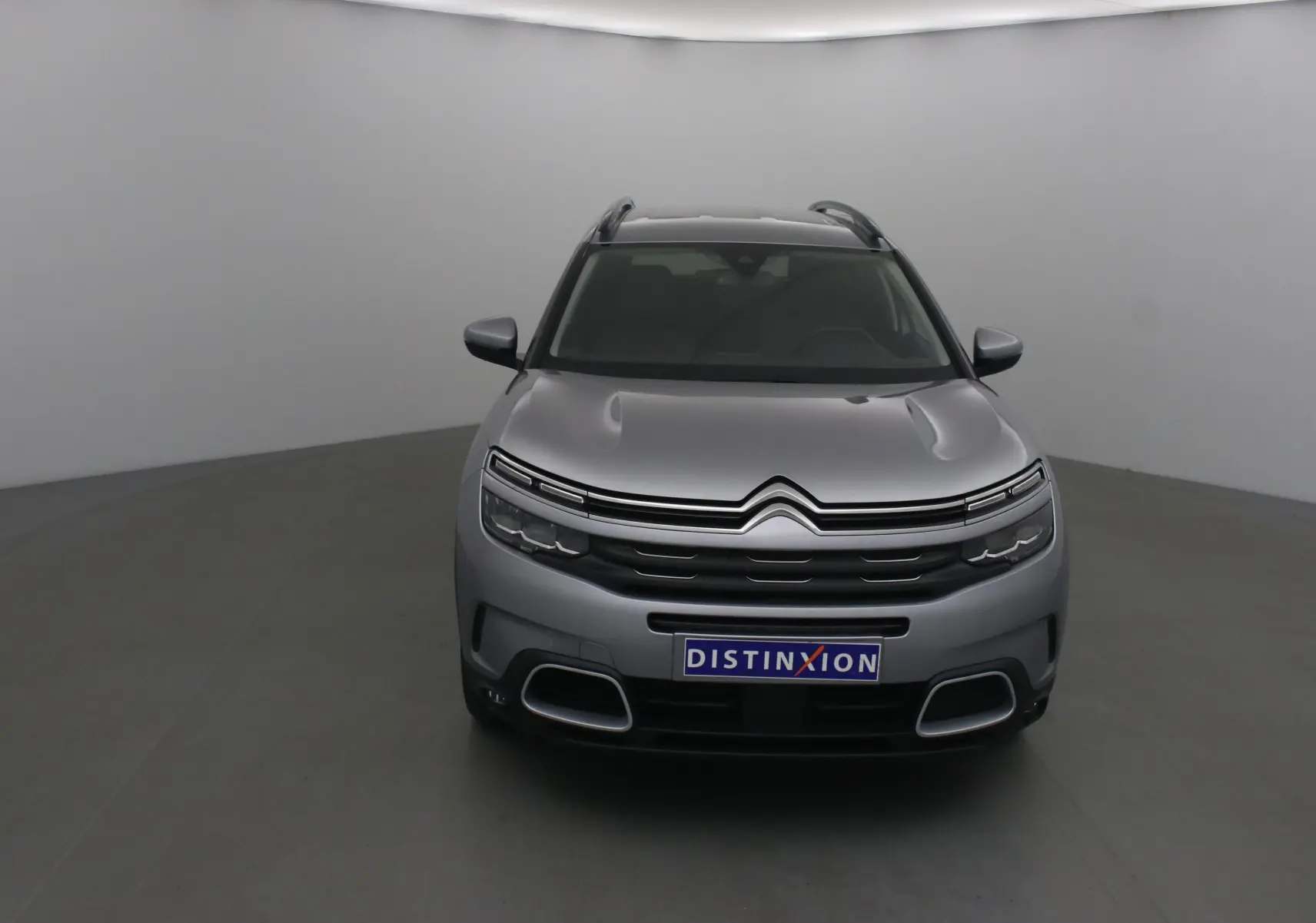 Citroën C5 Aircross gris Artense vue de face dans un studio, avec calandre distinctive et logo double chevron visible.