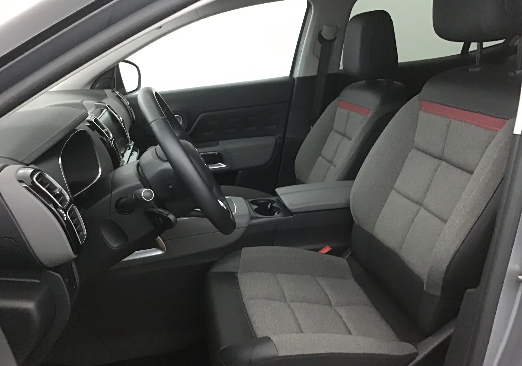 Intérieur avant droit du Citroën C5 Aircross gris, sièges tissu gris avec bande rouge et volant cuir noir.