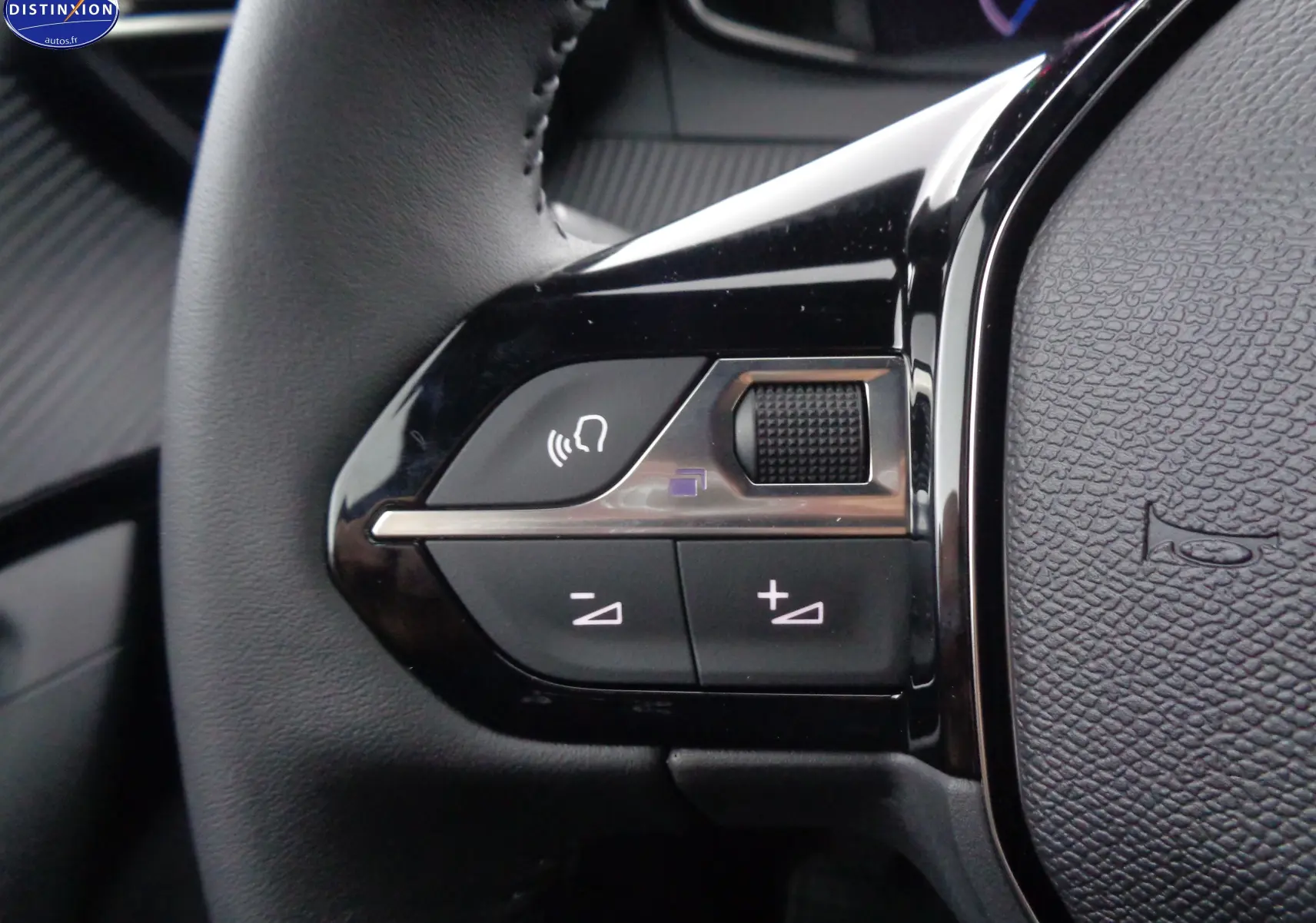 Gros plan sur les commandes vocales et volume au volant d'une Peugeot 2008 bleu Vertigo Metal, finition Allure 2023.
