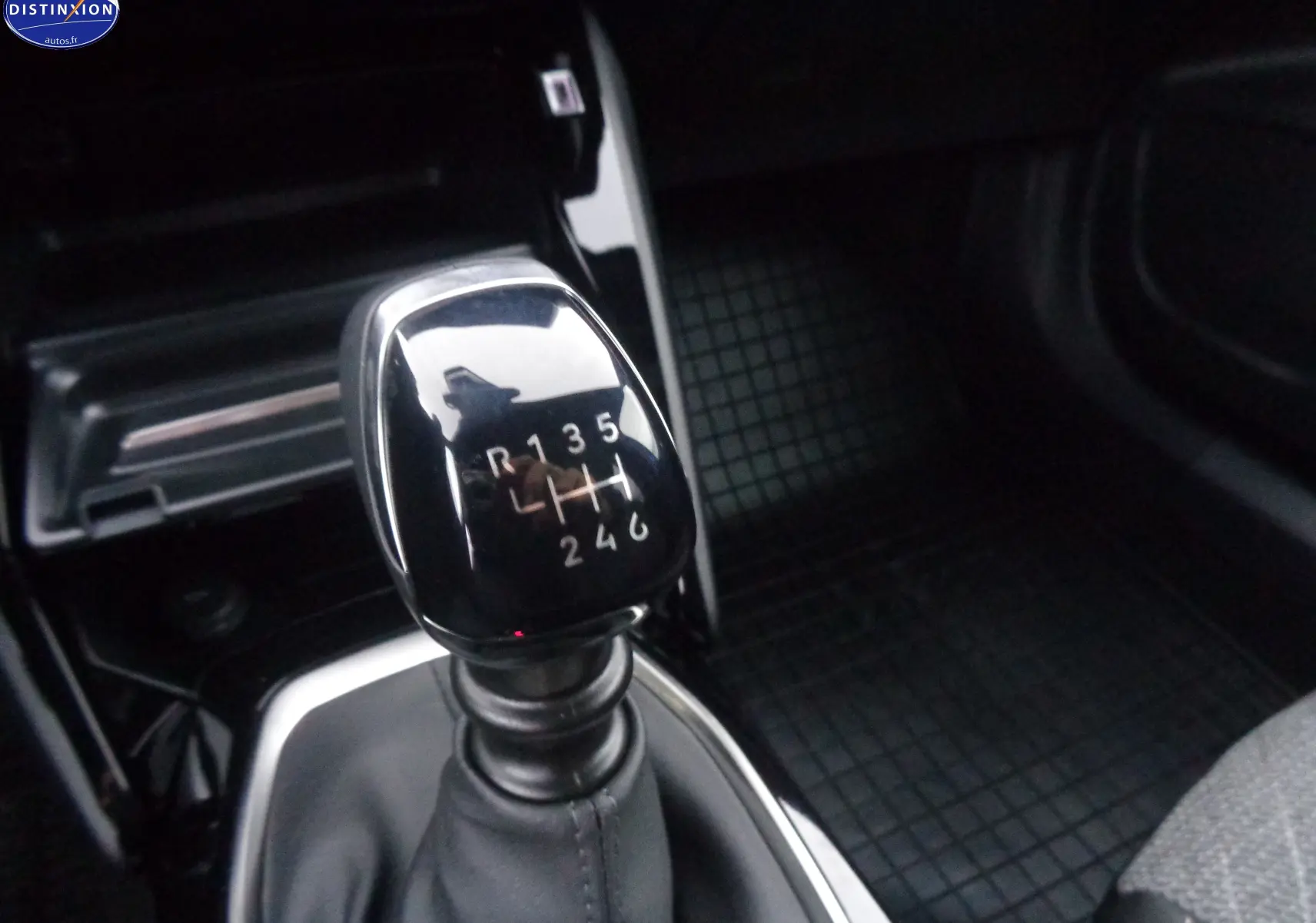 Le levier de vitesses manuel noir brillant de la Peugeot 2008 1.2 PureTech, intérieur sombre avec tapis caoutchouc.