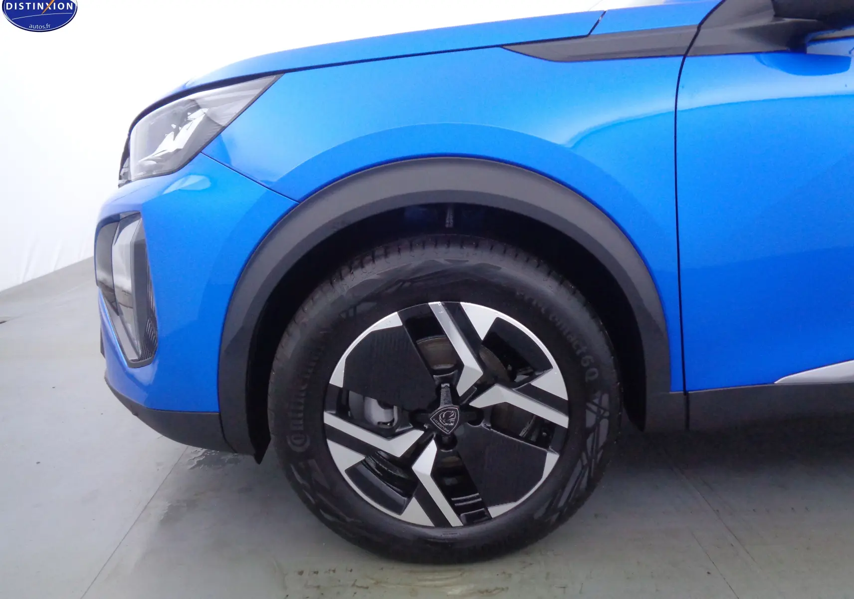 Gros plan sur la roue avant gauche et l'aile d'un Peugeot 2008 2023 bleu Vertigo Metal avec jante bi-ton noire et argent.