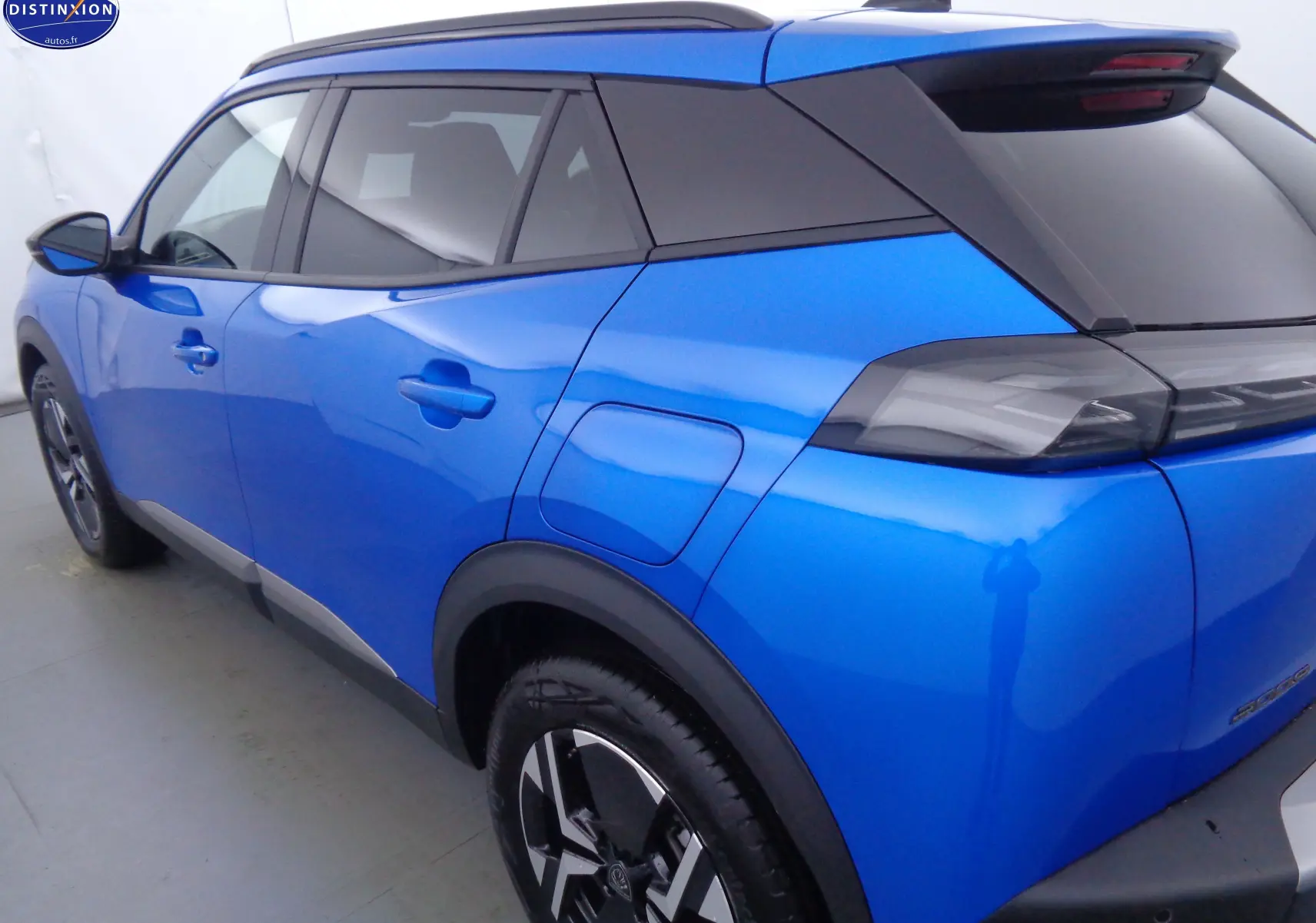 Vue 3/4 arrière droite du Peugeot 2008 bleu Vertigo Metal avec toit noir et jantes bi-ton noires.