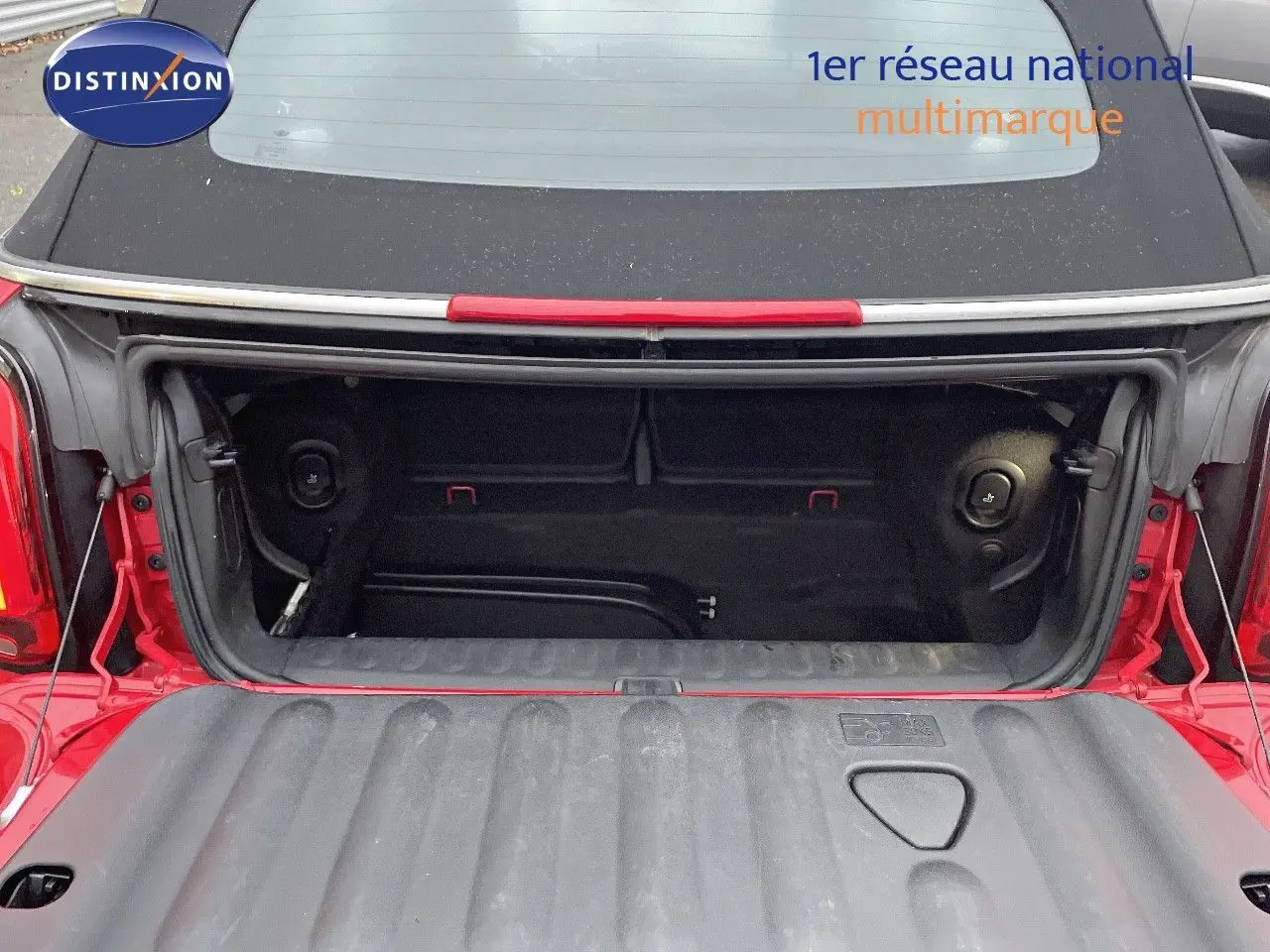 Coffre ouvert d'une MINI Cabriolet F57 rouge chili vue arrière, montrant l'espace de rangement intérieur.