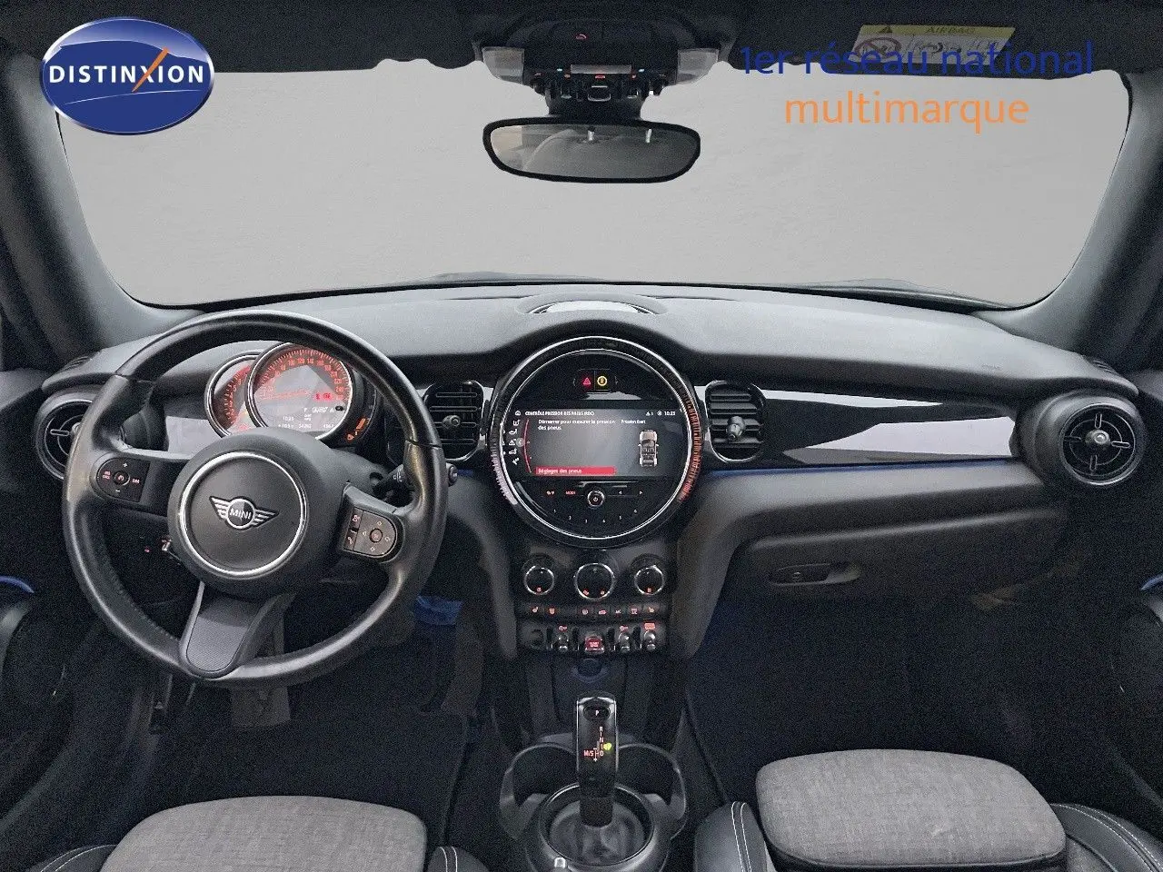 Vue intérieure frontale du tableau de bord noir et volant de la MINI Cabriolet F57, avec écran central rond allumé.