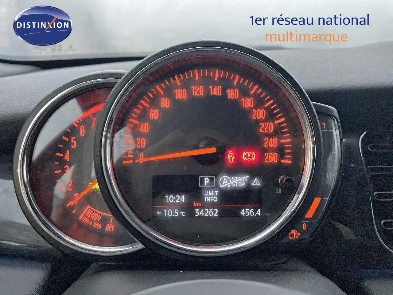 Gros plan sur le tableau de bord de la MINI Cabriolet rouge Chili, affichant le compteur de vitesse et les voyants allumés.
