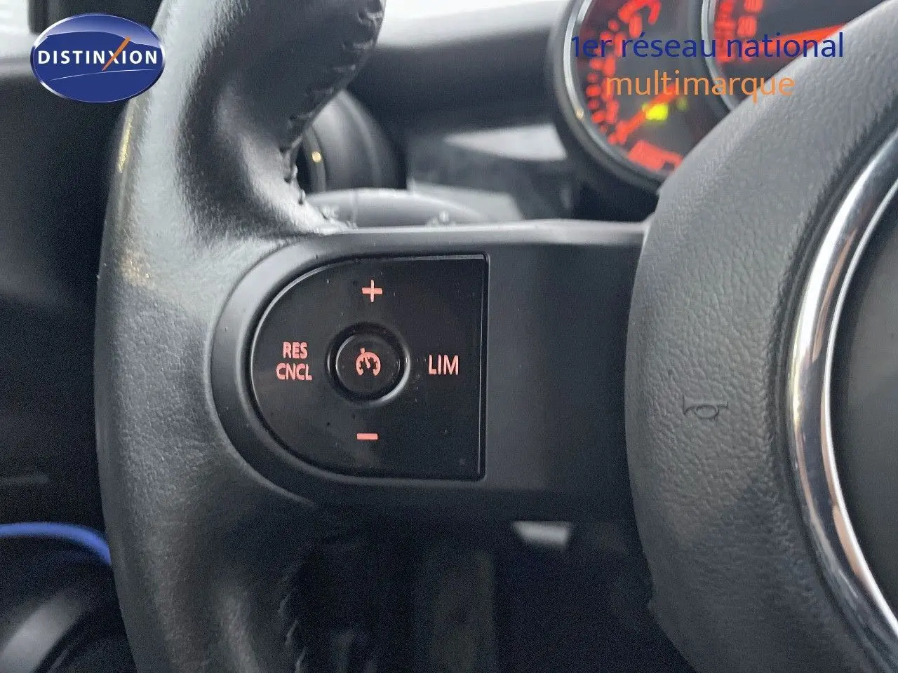 Gros plan sur les commandes de régulateur de vitesse au volant d’une MINI Cabriolet F57 rouge chili, intérieur noir.