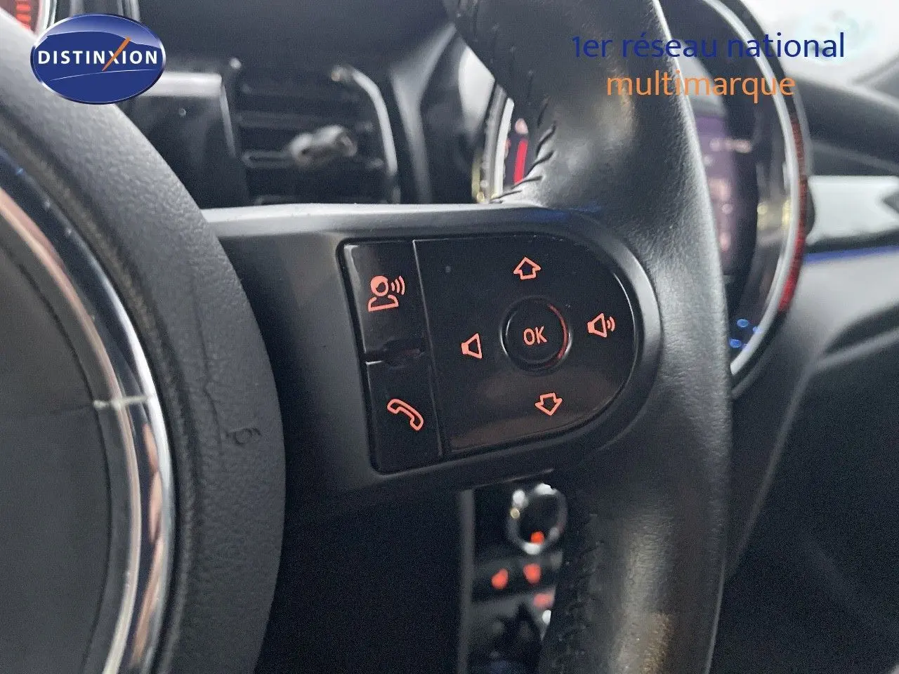 Gros plan sur les commandes du volant de la MINI Cabriolet F57 rouge chili, avec éclairage orange des boutons.