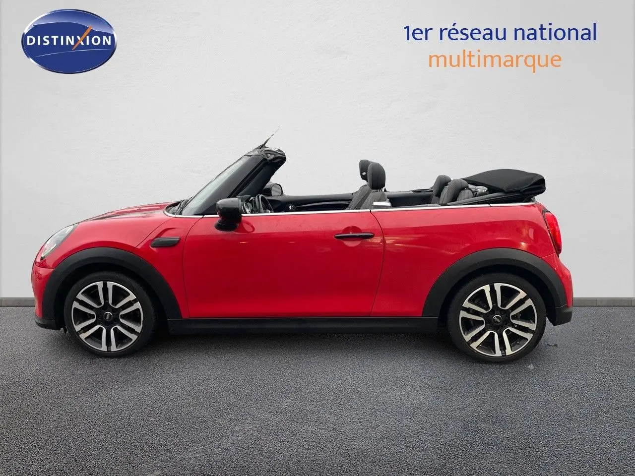 Vue de profil côté gauche d'une MINI Cabriolet rouge chili avec capote noire partiellement ouverte.