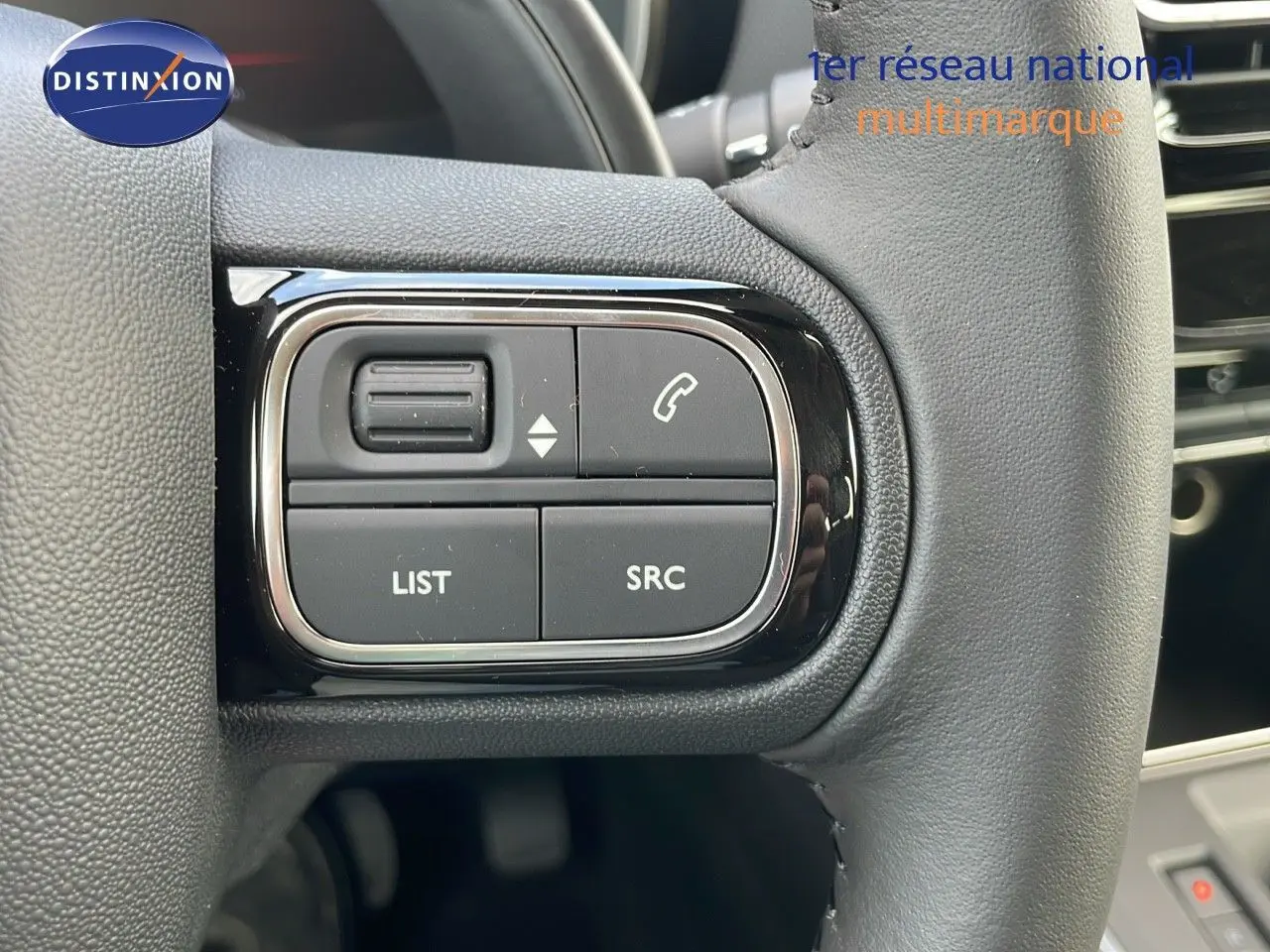 Gros plan sur les commandes gauche du volant cuir noir du Citroën C5 Aircross blanc, avec boutons audio et téléphone.