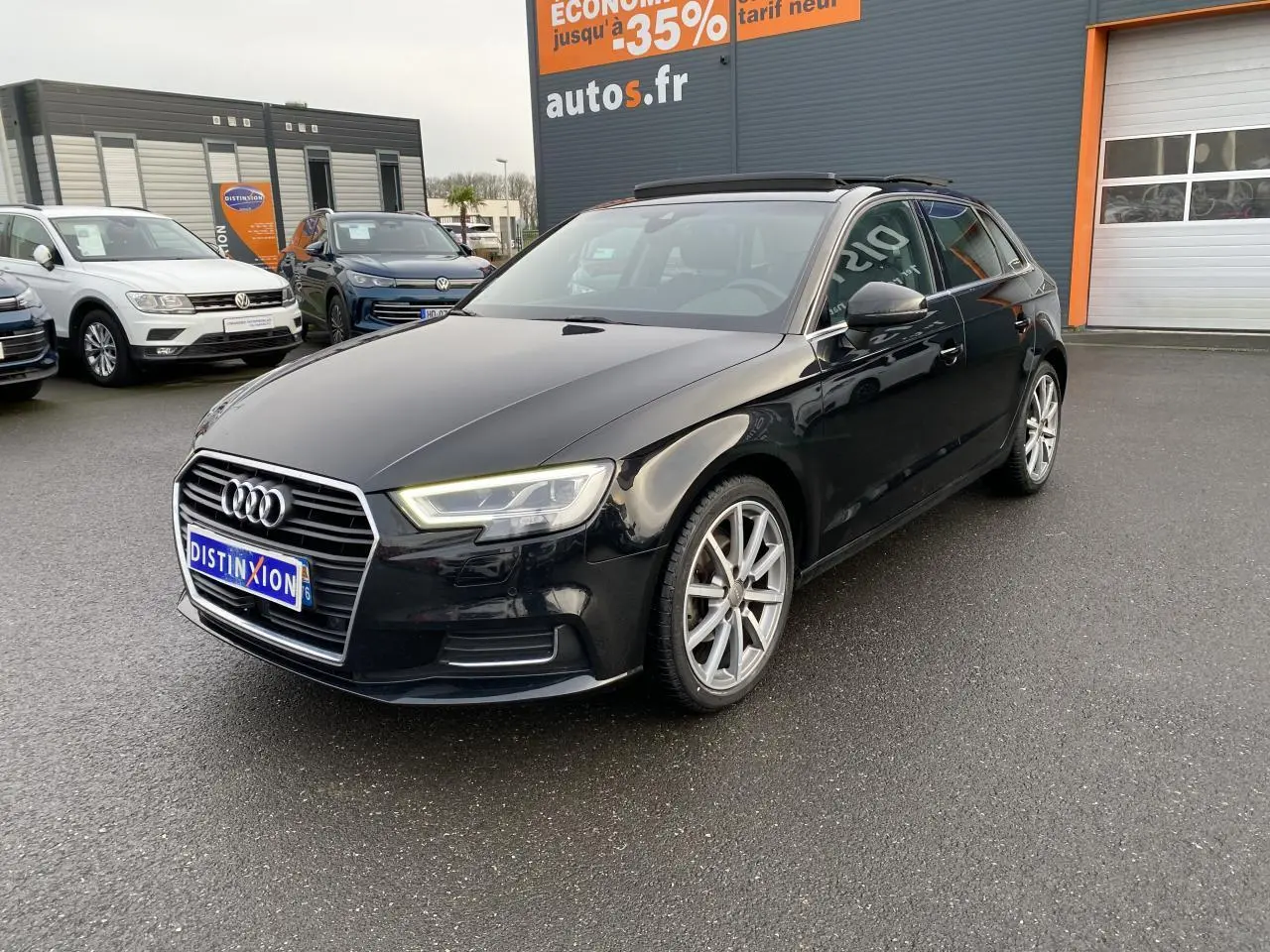 Audi A3 Sportback noir vue 3/4 avant droit avec toit panoramique et jantes alliage visibles.