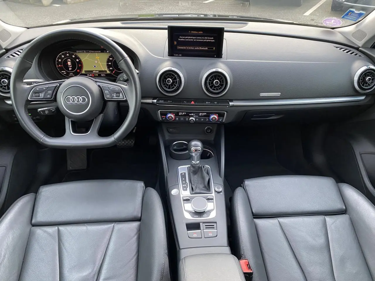 Vue intérieure avant de l'Audi A3 Sportback 2019, tableau de bord noir avec volant multifonction et console centrale moderne.