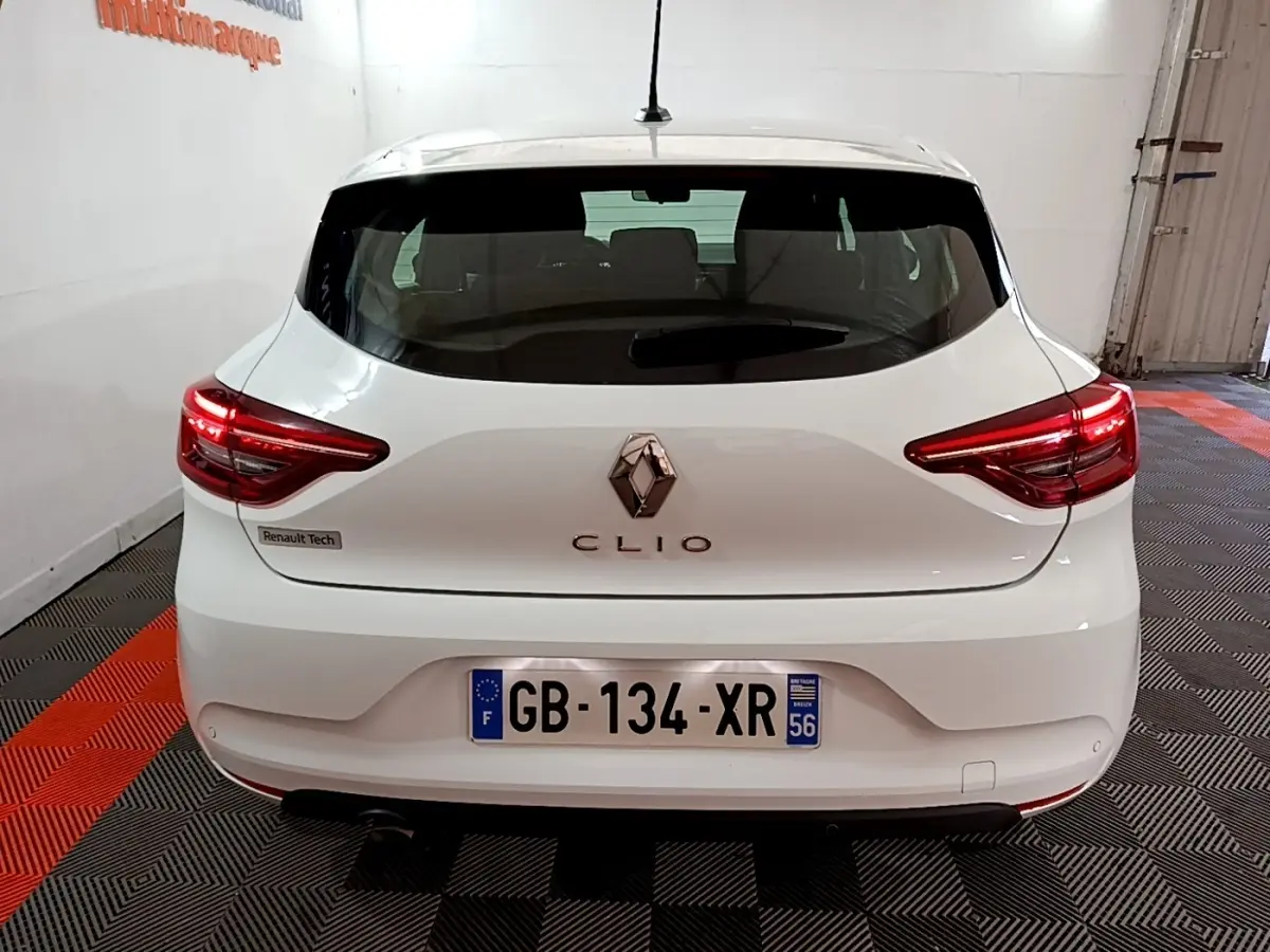 Vue arrière d'une Renault Clio blanche 2021 avec feux LED et logo central bien visibles dans un garage.