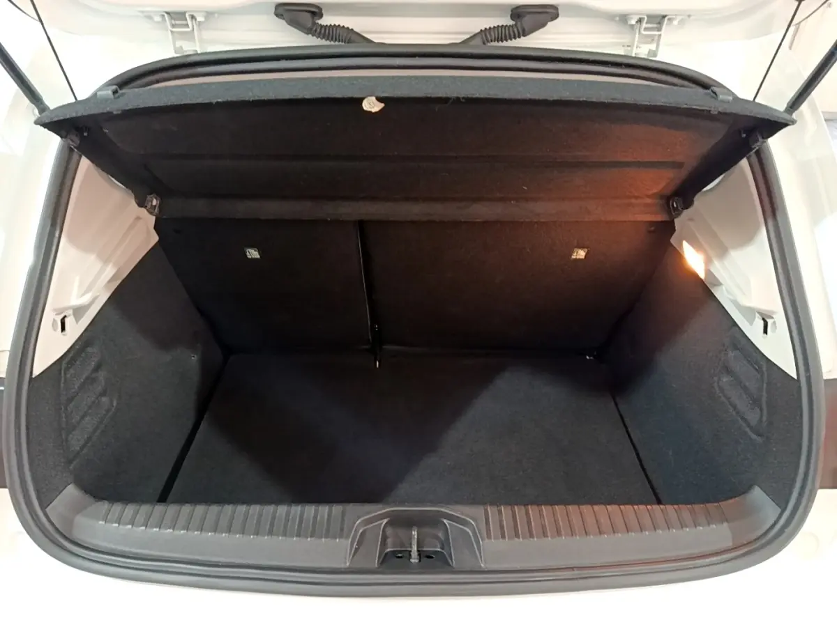 Coffre ouvert vu de l'arrière d'une Renault Clio Business blanche, intérieur noir et éclairage latéral droit.