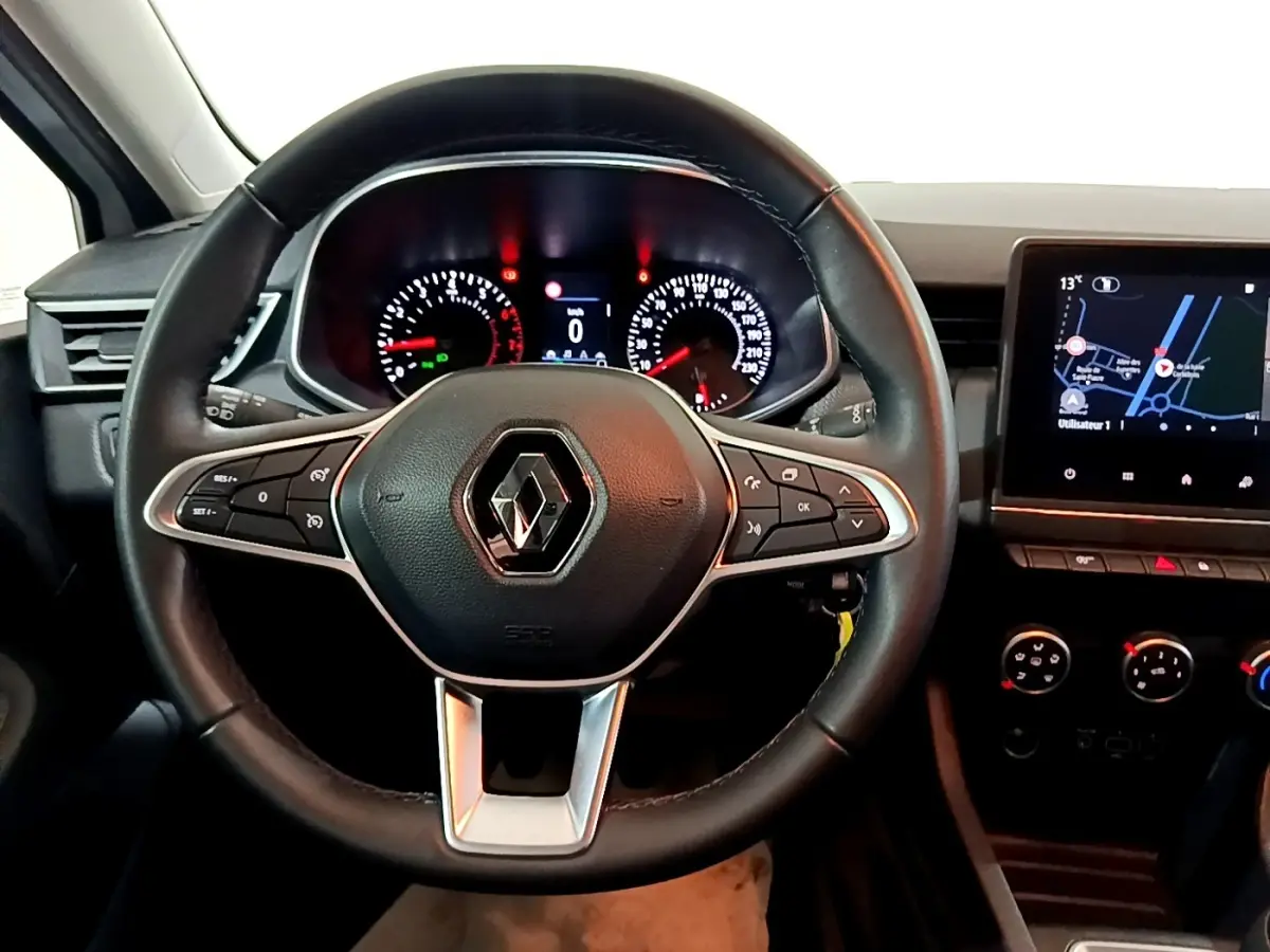 Vue intérieure centrée sur le volant noir Renault Clio 2021 avec tableau de bord et écran tactile de navigation.