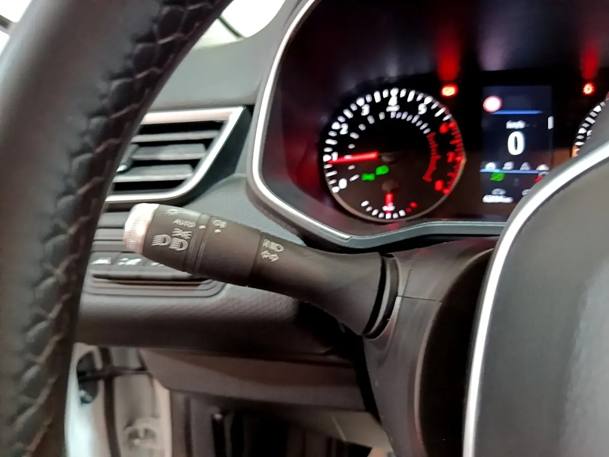 Intérieur Renault Clio blanc 2021, vue sur le tableau de bord avec compte-tours et commandes des phares sur la gauche du volant.