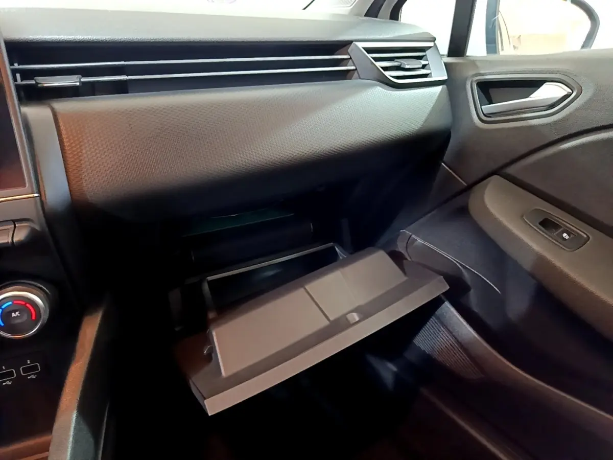 Intérieur de la Renault Clio Business blanc, vue côté passager avec boîte à gants ouverte et tableau de bord noir.