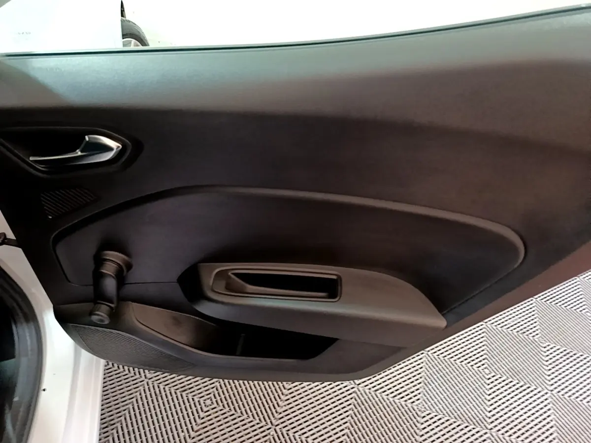 Vue intérieure de la porte avant gauche noire d'une Renault Clio blanche avec poignée et manivelle de vitre.