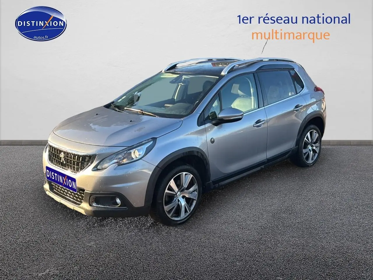 Peugeot 2008 gris clair vue 3/4 avant droit avec barres de toit et jantes alu diamantées.