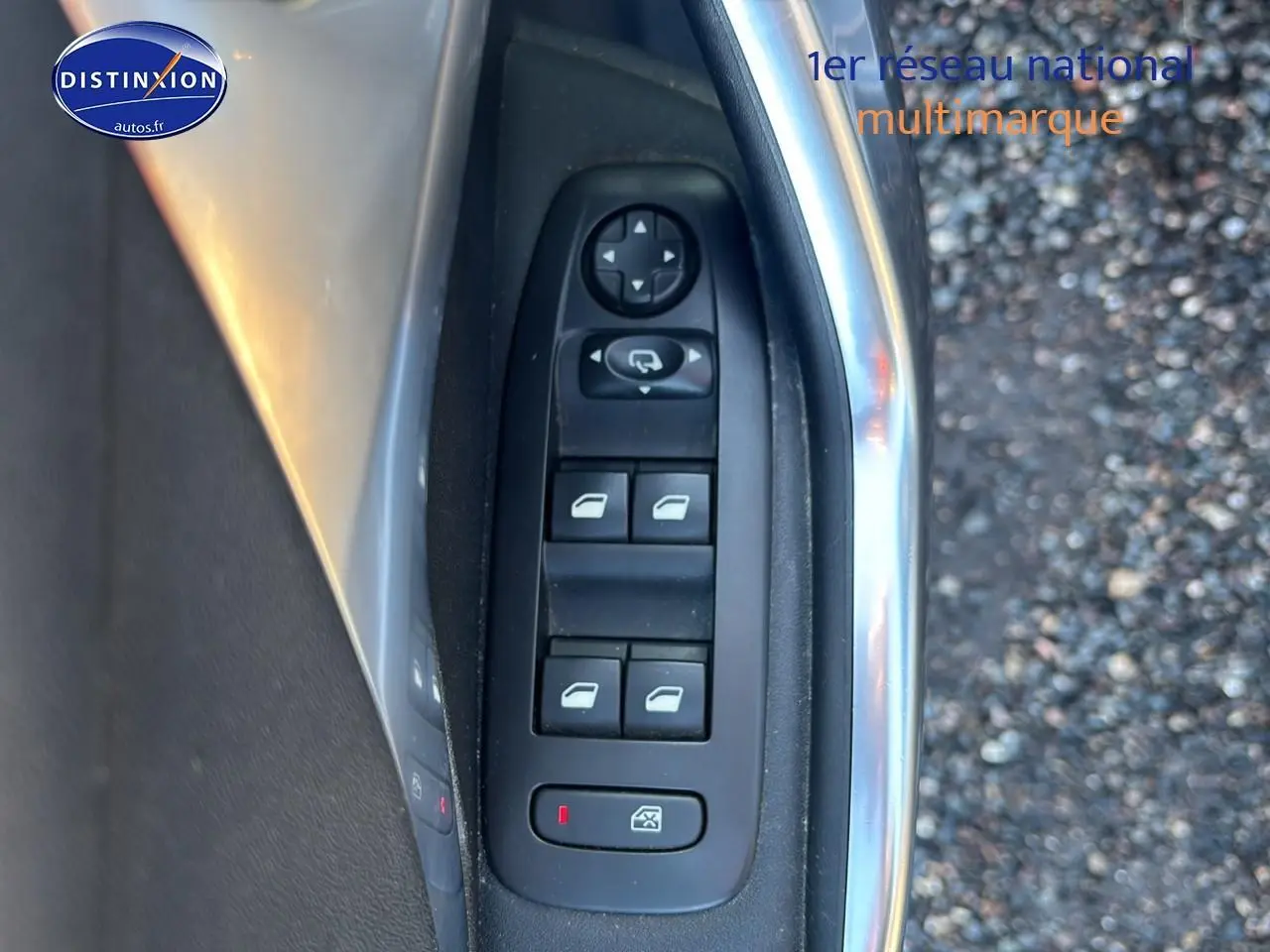 Gros plan sur les commandes des vitres électriques côté conducteur d’une Peugeot 2008 gris clair.