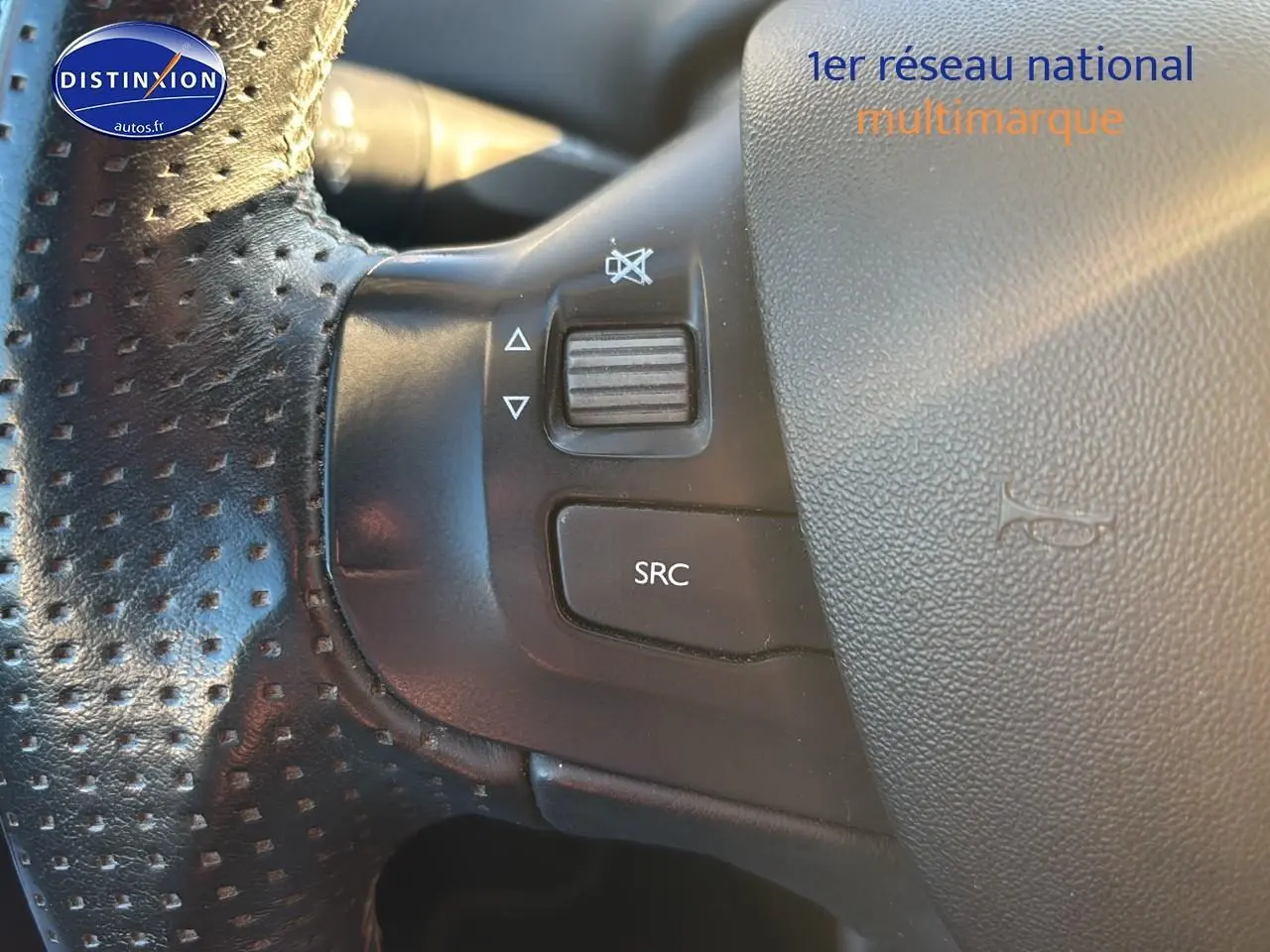 Gros plan sur les commandes gauche du volant cuir perforé d’un Peugeot 2008 gris clair 2019.