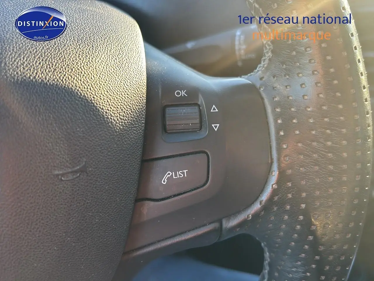 Gros plan sur le volant cuir perforé de la Peugeot 2008 2019 avec commandes multifonctions visibles.