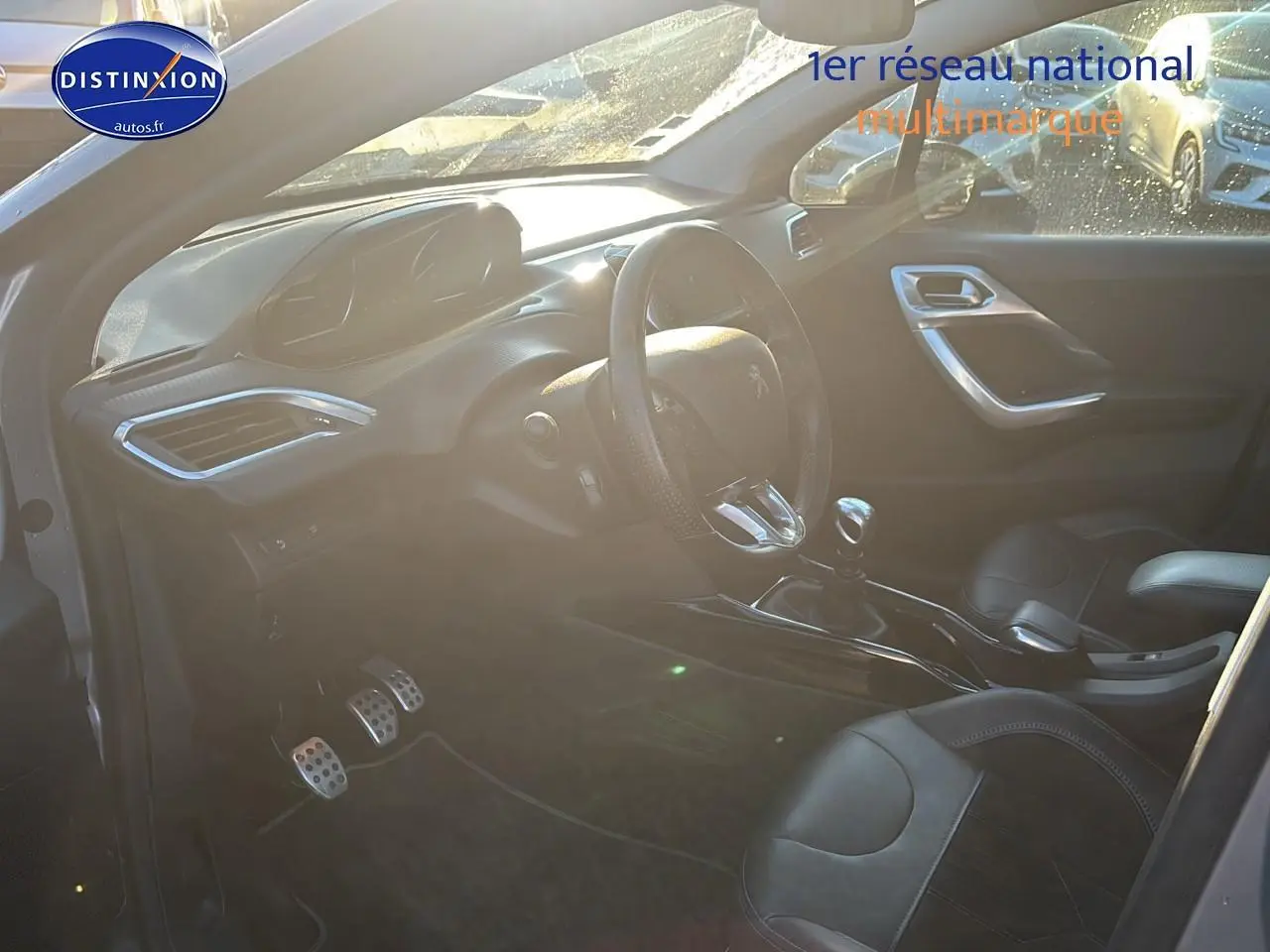 Vue intérieure côté conducteur du Peugeot 2008 gris clair, mettant en valeur le volant cuir et la boîte manuelle.