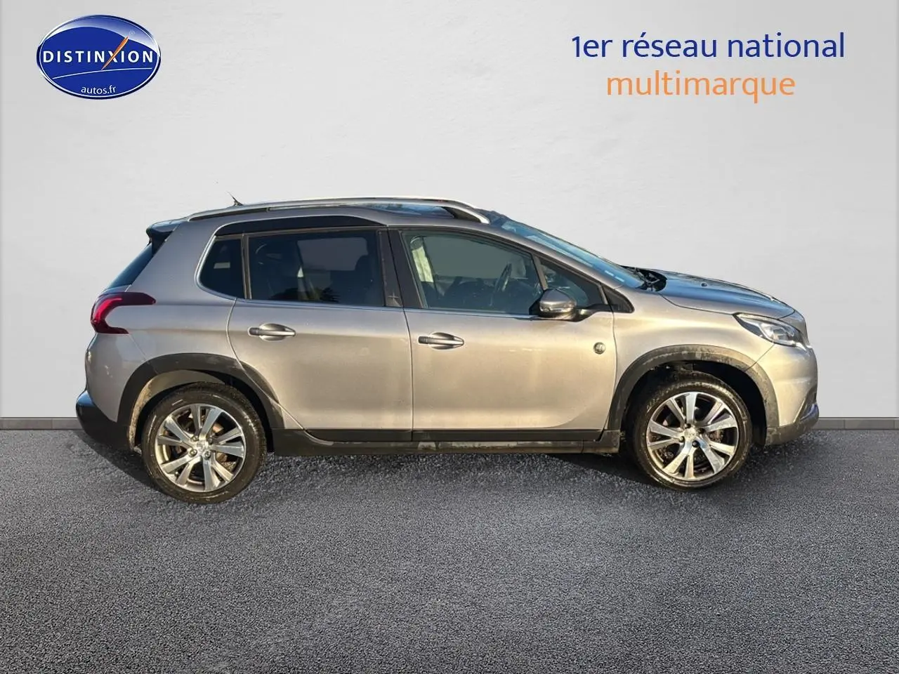 Vue de profil côté gauche d’un Peugeot 2008 gris clair avec barres de toit et jantes alliage.