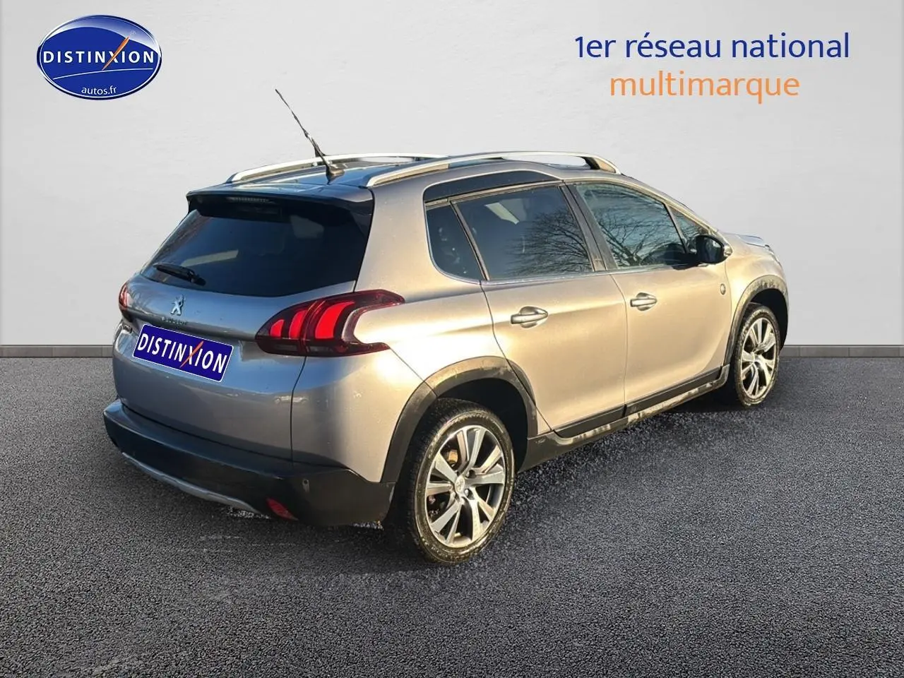 Peugeot 2008 gris clair vue 3/4 arrière droit avec barres de toit et vitres teintées sur fond neutre.