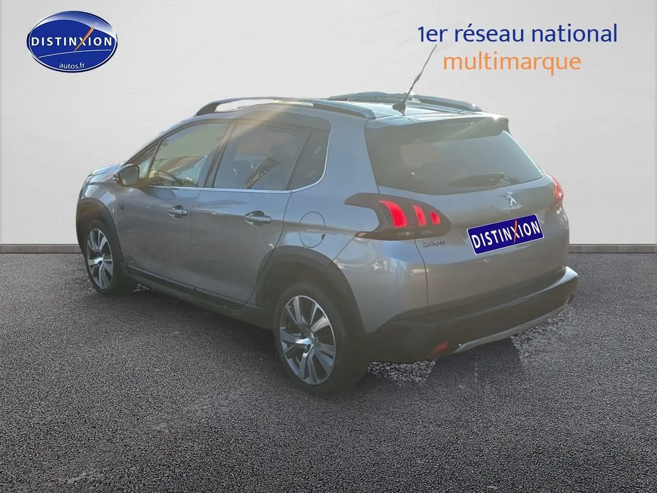 Peugeot 2008 gris clair vue 3/4 arrière droit, avec feux arrière LED et barres de toit visibles.