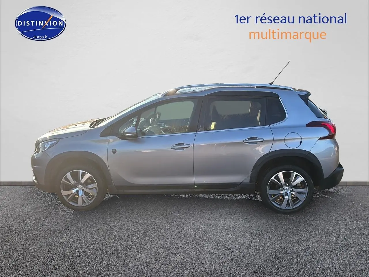 Profil droit d'un Peugeot 2008 gris clair de 2019 avec jantes alu et barres de toit visibles.