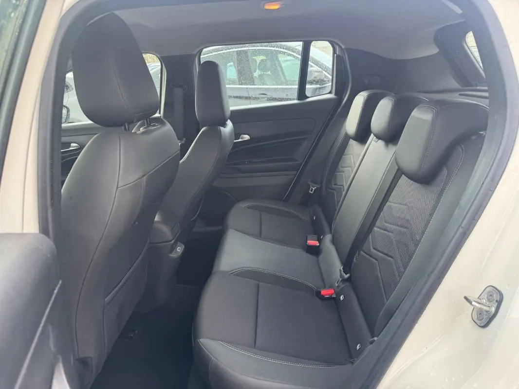 Vue intérieure côté gauche des sièges arrière noirs en tissu et cuir du Jeep Avenger blanc 2025, porte ouverte.
