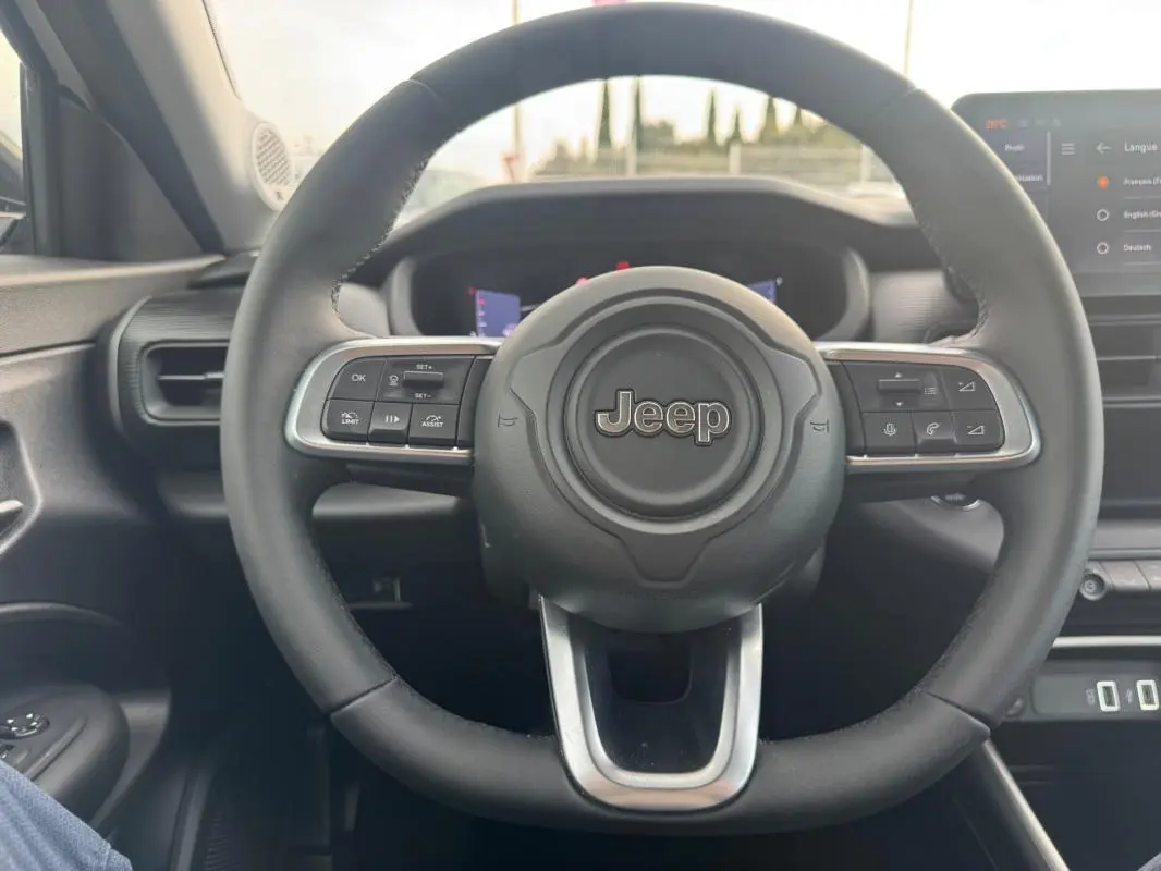 Vue intérieure centrée sur le volant noir du Jeep Avenger 2025 avec commandes multifonctions et tableau de bord numérique.
