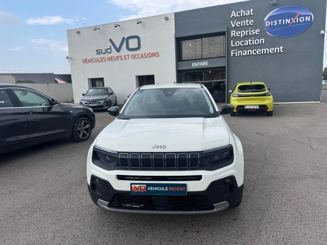 Vue de face d'un Jeep Avenger blanc 2025 avec calandre noire et plaques d'immatriculation du concessionnaire.