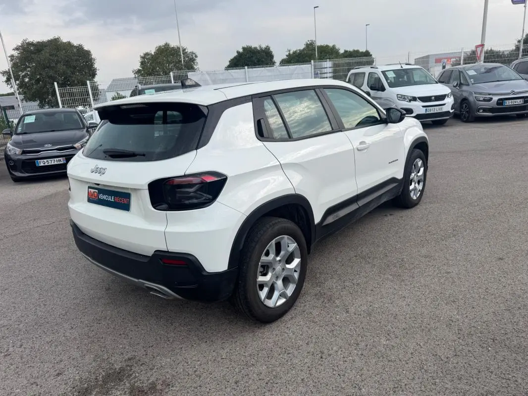 Jeep Avenger blanc en 3/4 arrière droit, avec jantes alliage 17 pouces et feux arrière teintés noirs.